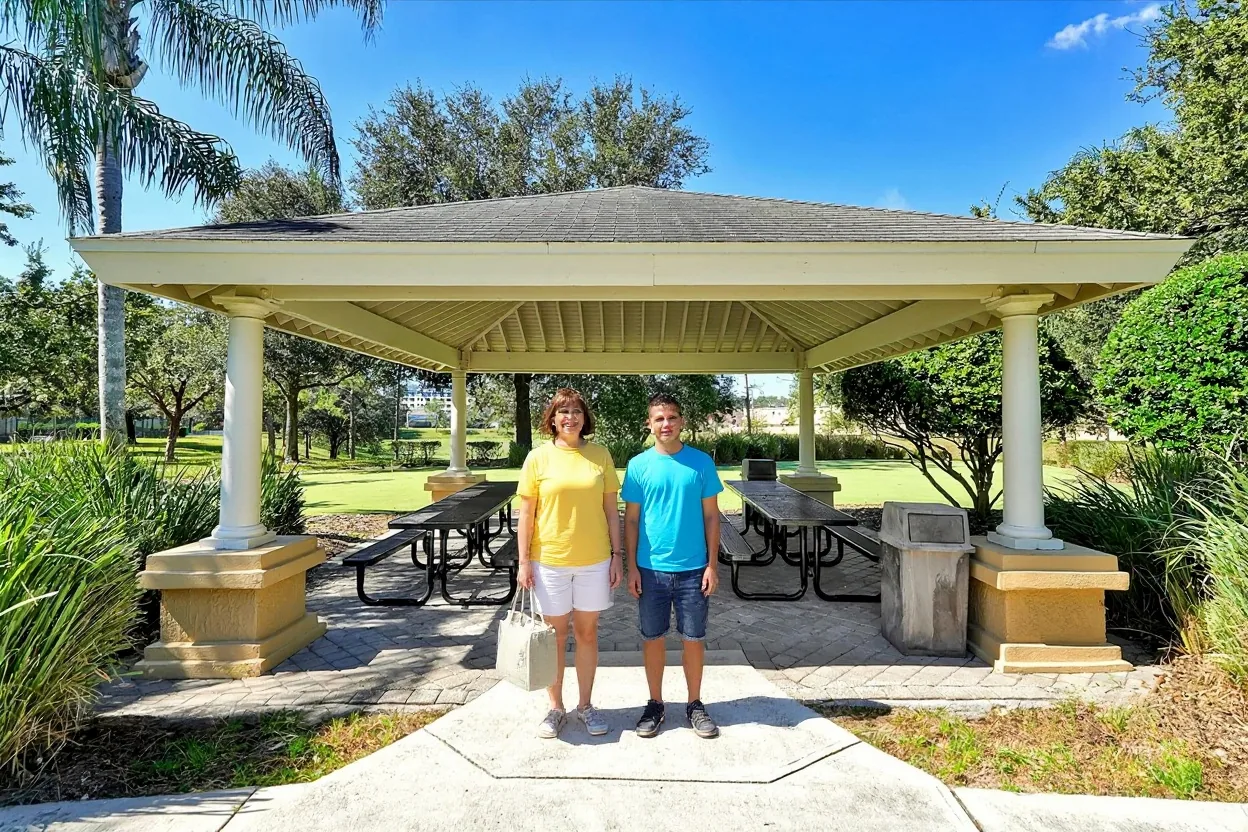 A mom and her son standing by a picnic pavilion with a small lunch bag