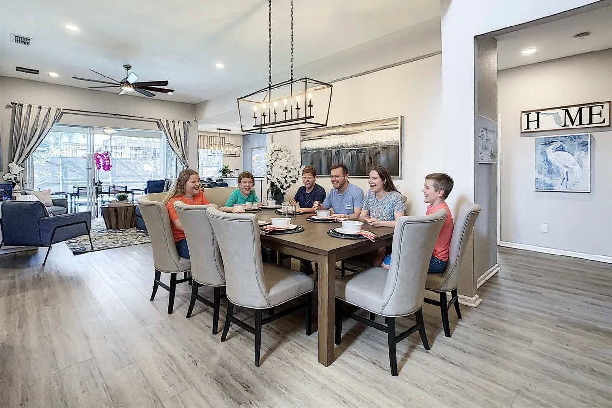 An ordinary family of six sitting at the existing dining table passing around two pizza boxes and laughing, parents and four kids of different ages