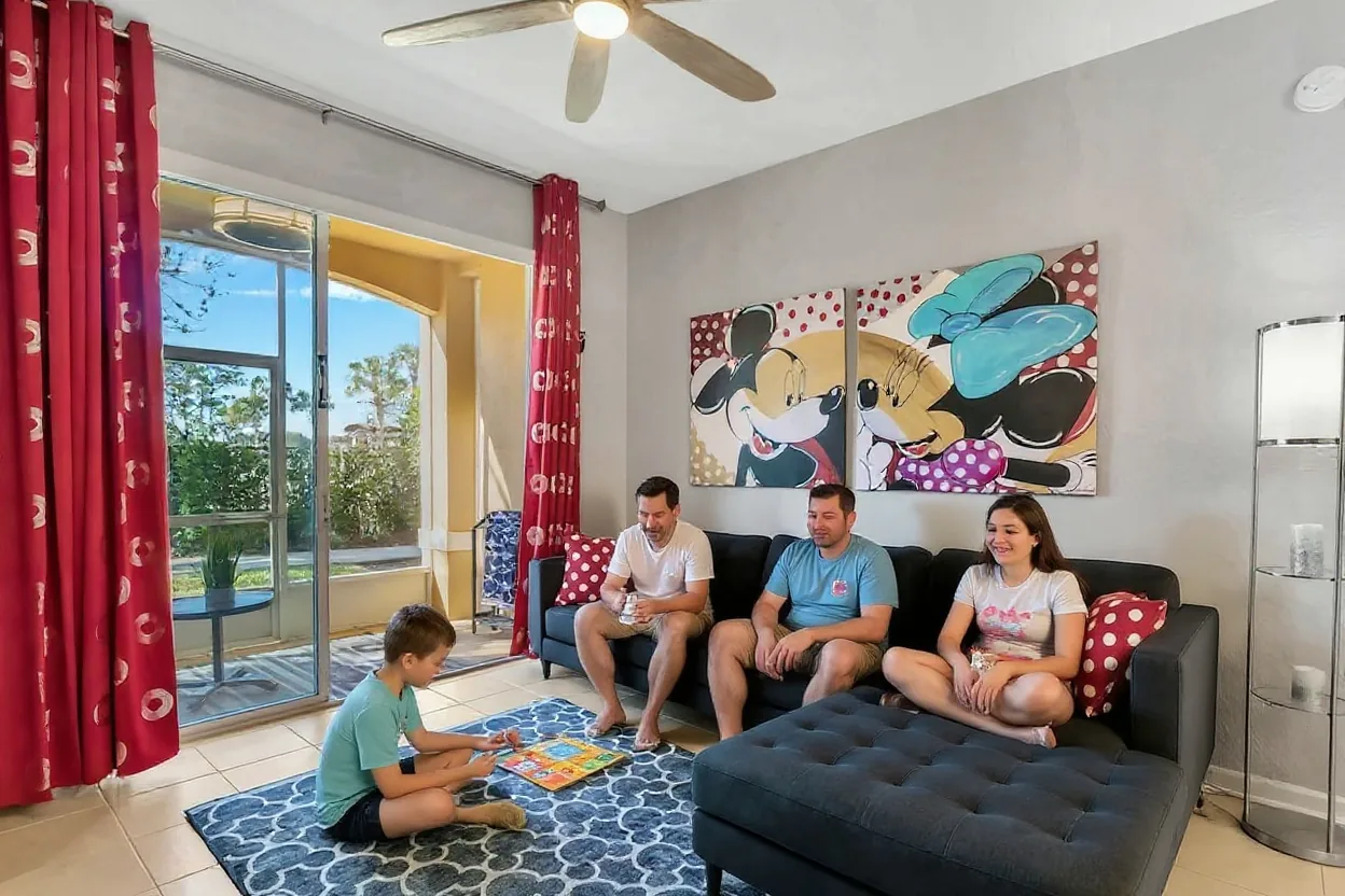 An ordinary family relaxing in the existing living room: parents on the sofa with coffee and two kids in plain t-shirts playing a board game on the