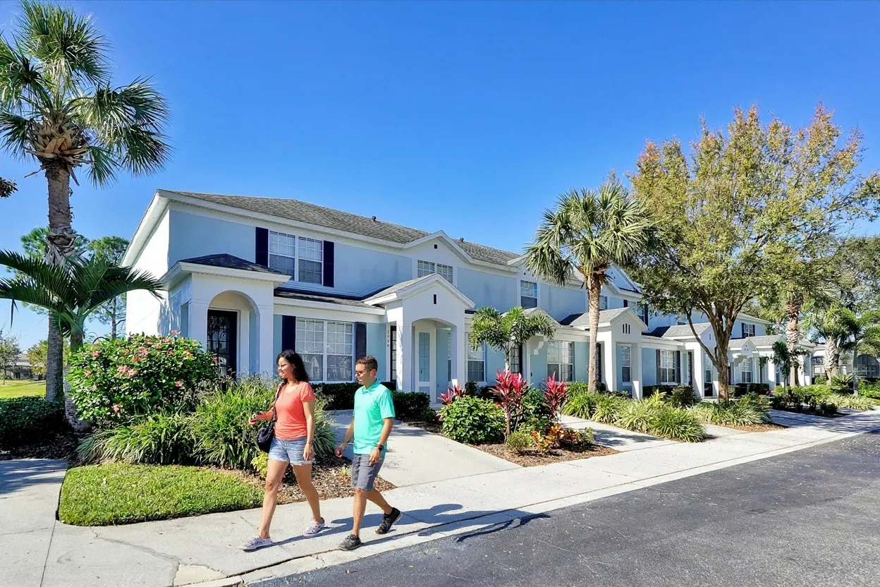 A couple walking past the Windsor Hills townhouses on a sunny morning, heading out for a park day