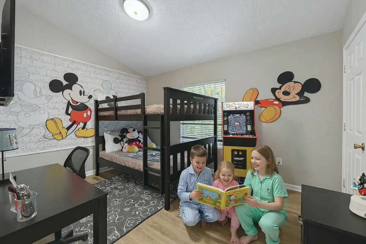 Three cousins in pajamas reading a picture book together in a themed bunk room
