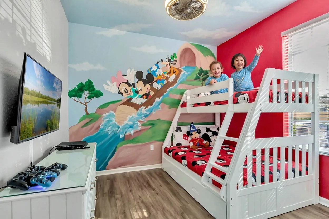 Two kids in pajamas on the existing bunk bed, one on the top bunk and one on the bottom, both grinning and waving