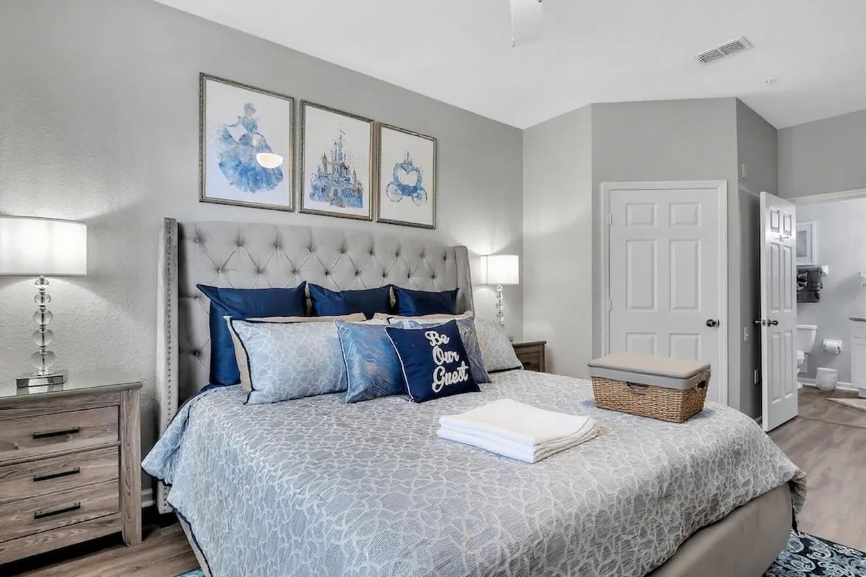 Neat stacks of freshly folded t-shirts, shorts and towels and a plain woven laundry basket on the existing bed, and an open plain suitcase