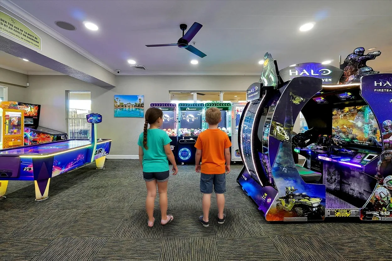 Two kids looking over the claw machines and arcade cabinets in the Windsor Hills games room