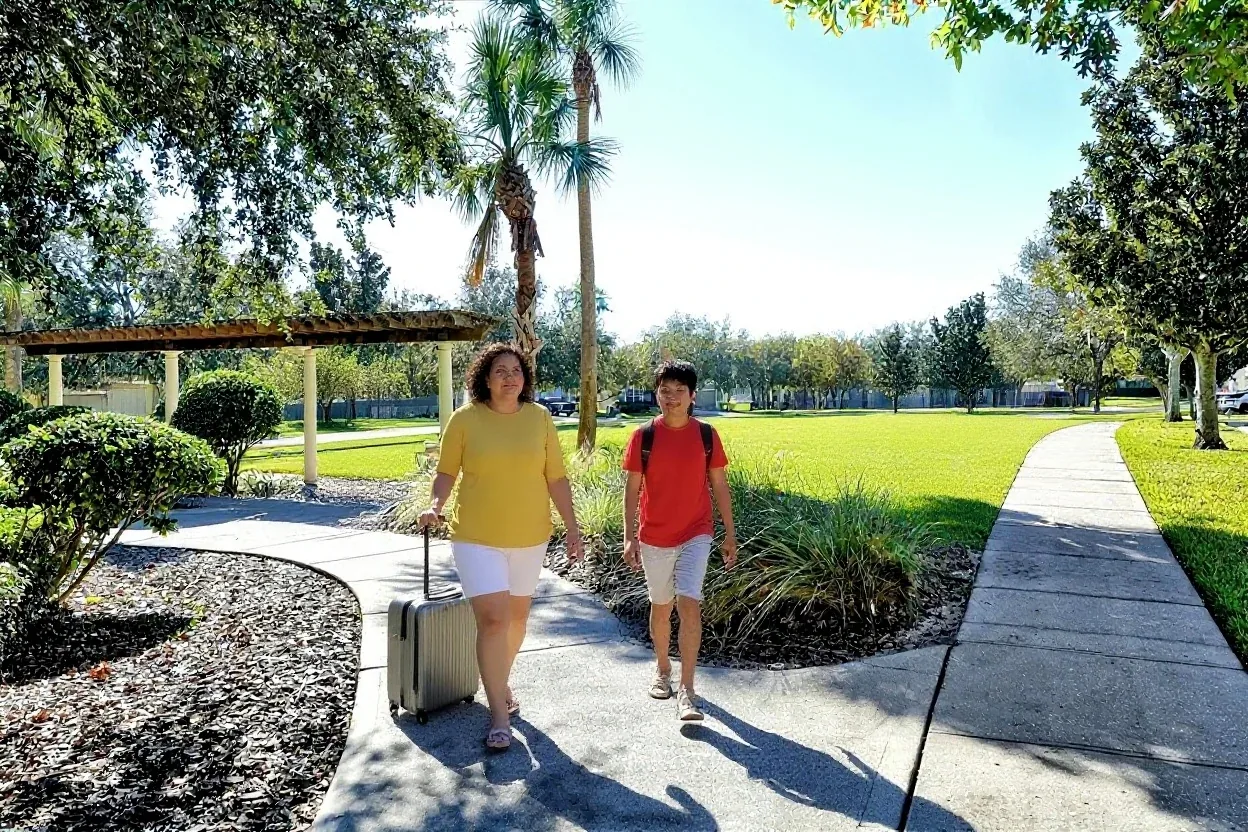 A mom and son arriving with a suitcase on a garden walkway at Windsor Hills Resort