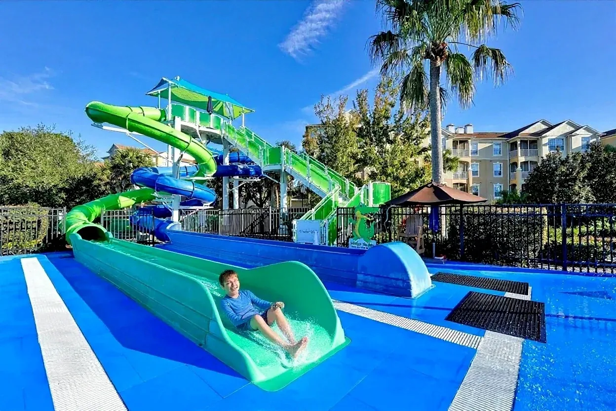 A boy splashing down the green water slide at the Windsor Hills water park