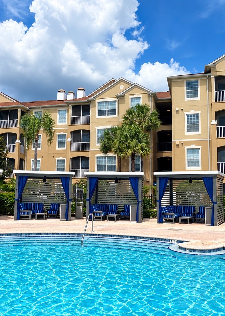 Poolside cabana rentals with blue curtains next to the resort pool, condo buildings and palm trees at Windsor Hills Resort